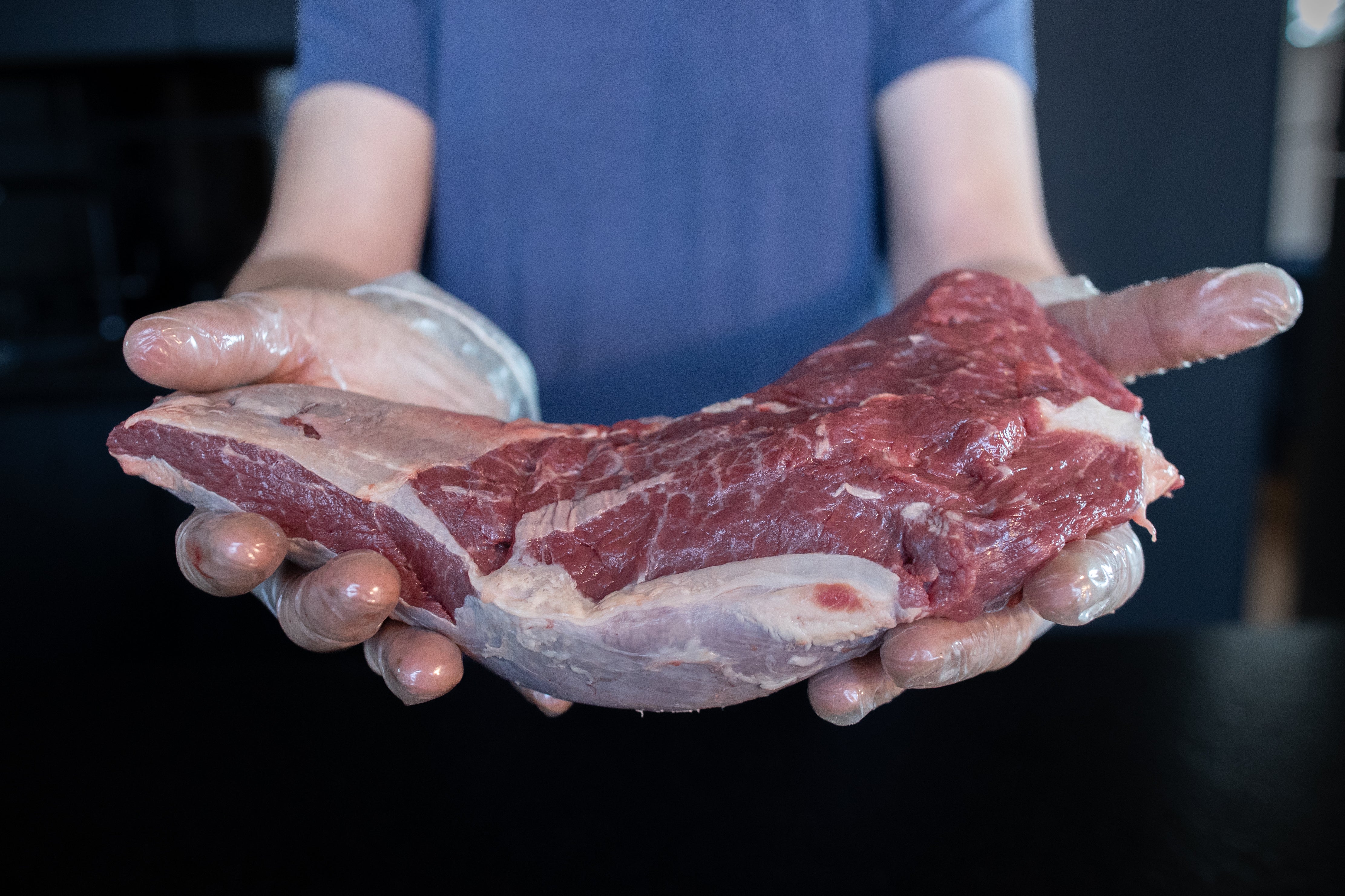 Řezník drží hovězí váleček z plece Fox Meadows – kvalitní maso pro pomalu tažené pokrmy