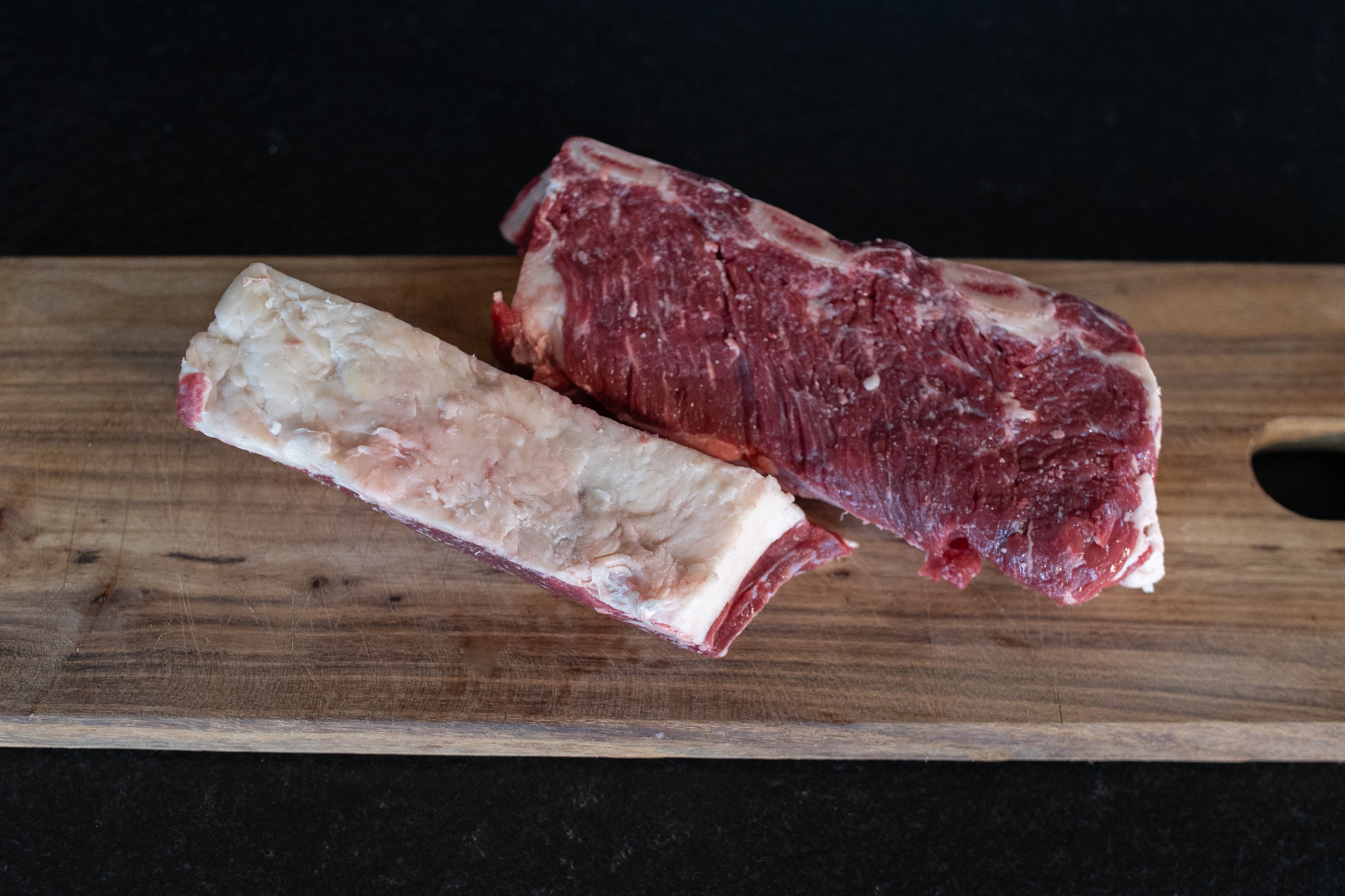 Hovězí žebra s kostí Fox Meadows na dřevěném prkénku – připravená k pečení a grilování