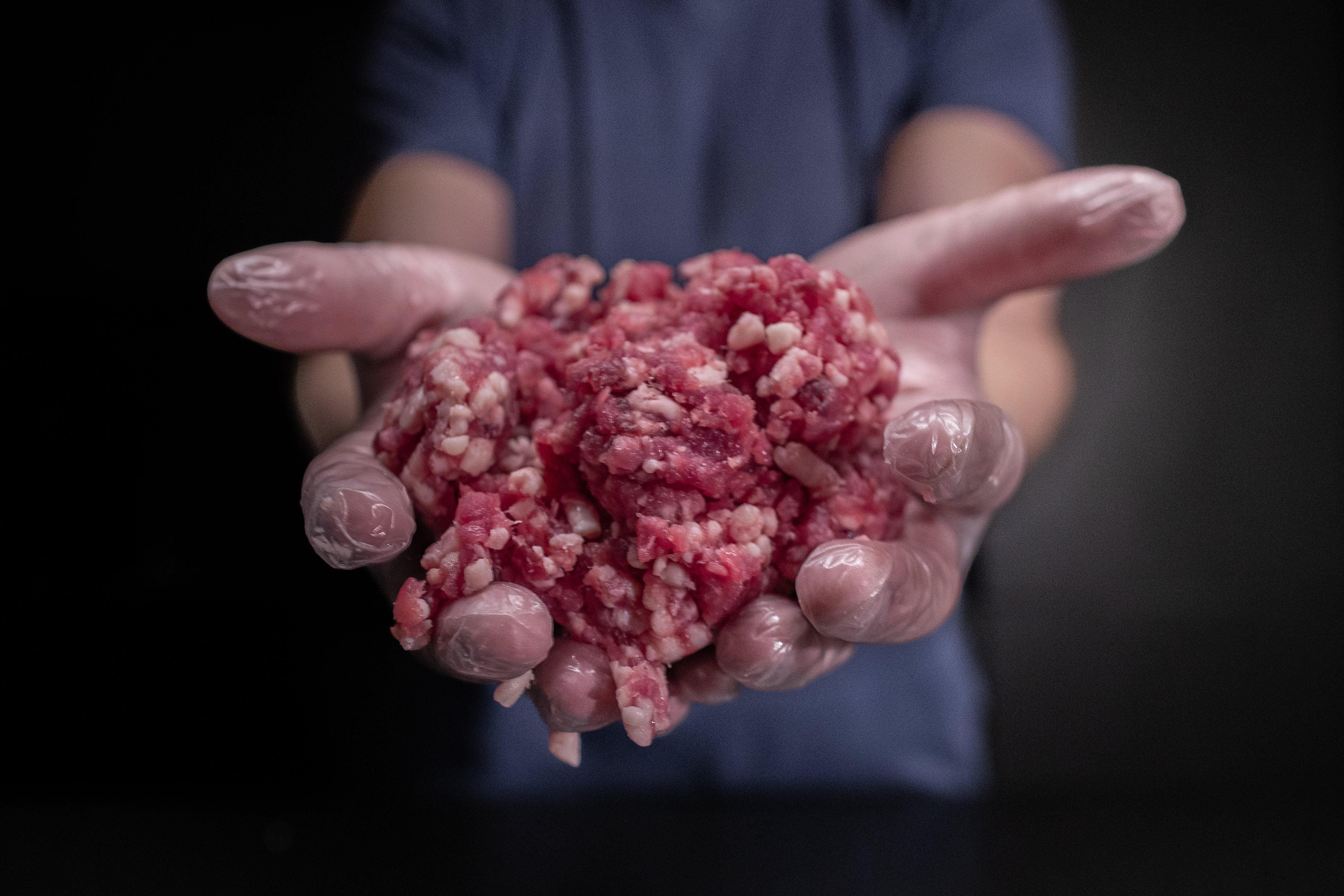 Řezník drží mleté maso na burgery Fox Meadows – kvalitní směs pro perfektní burgery