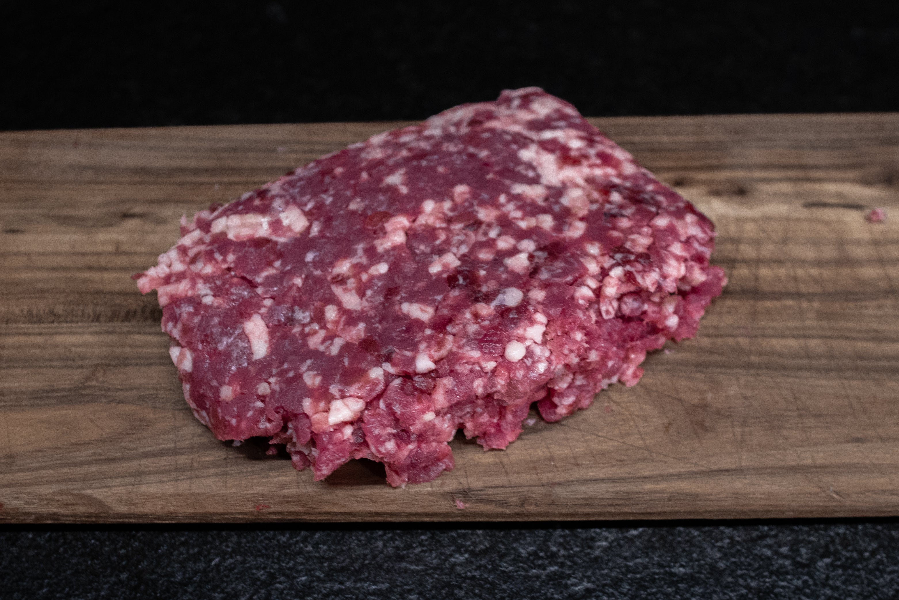 Mleté maso na burgery Fox Meadows na dřevěném prkénku – připravené k pečení a grilování